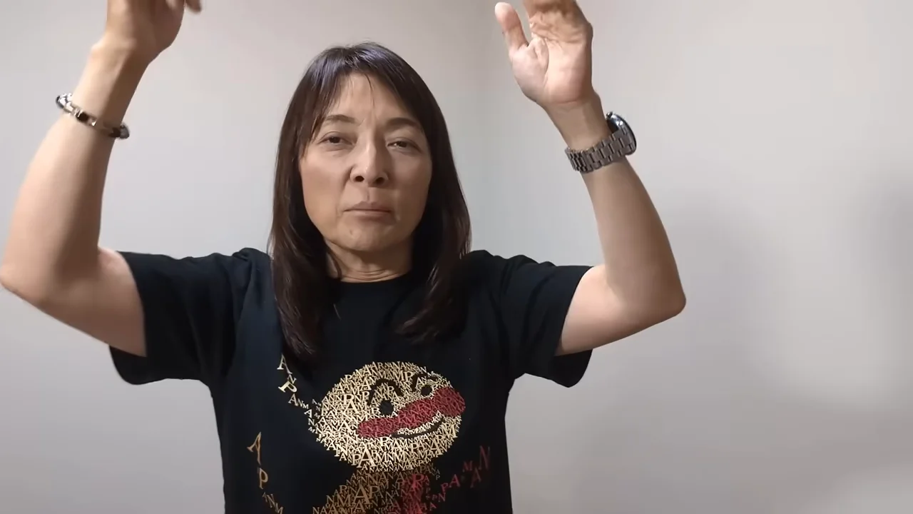 女性が両手を上げて身振りを交えながら話している。