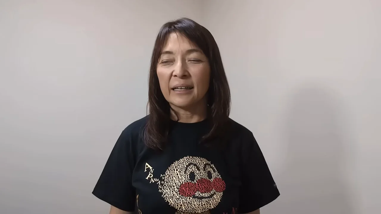 女性が目を細めて微笑みながらカメラに向かって話している。