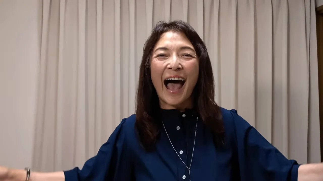 女性が両手を広げて口を大きく開け、笑顔を見せています。