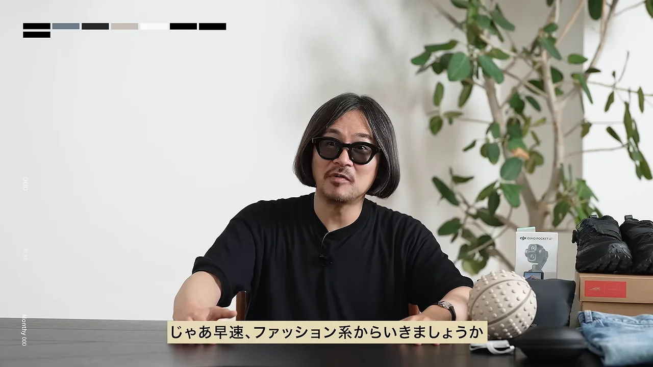 机の前に座って話す黒い服を着た男性