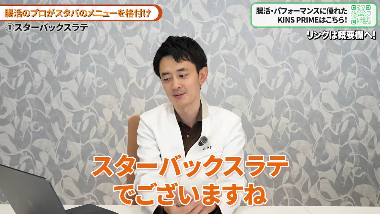 白衣を着た男性がデスクに向かい、視線を落として話している様子