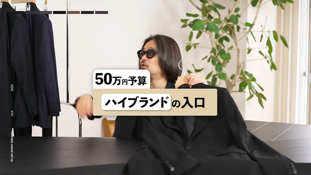 男性がハンガーに掛かった黒いジャケットを持ち上げて見せています。