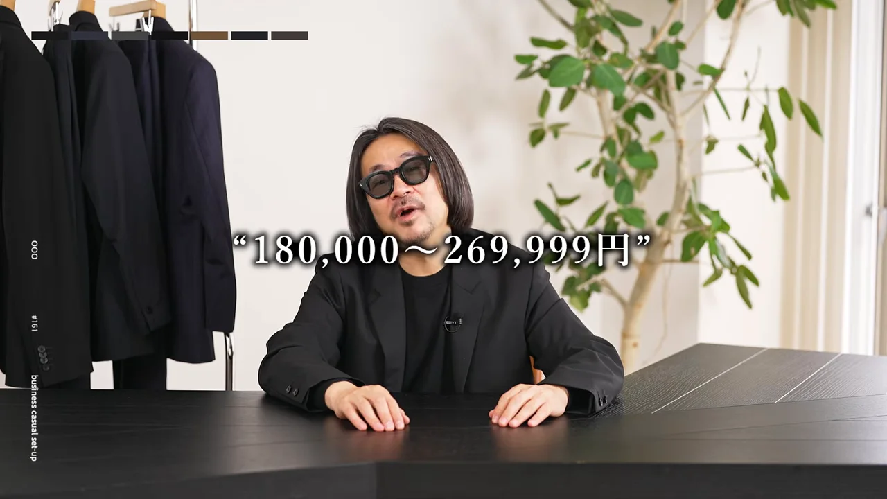 男性が黒いテーブルに両手を置いて座り、前を向いて話しています。