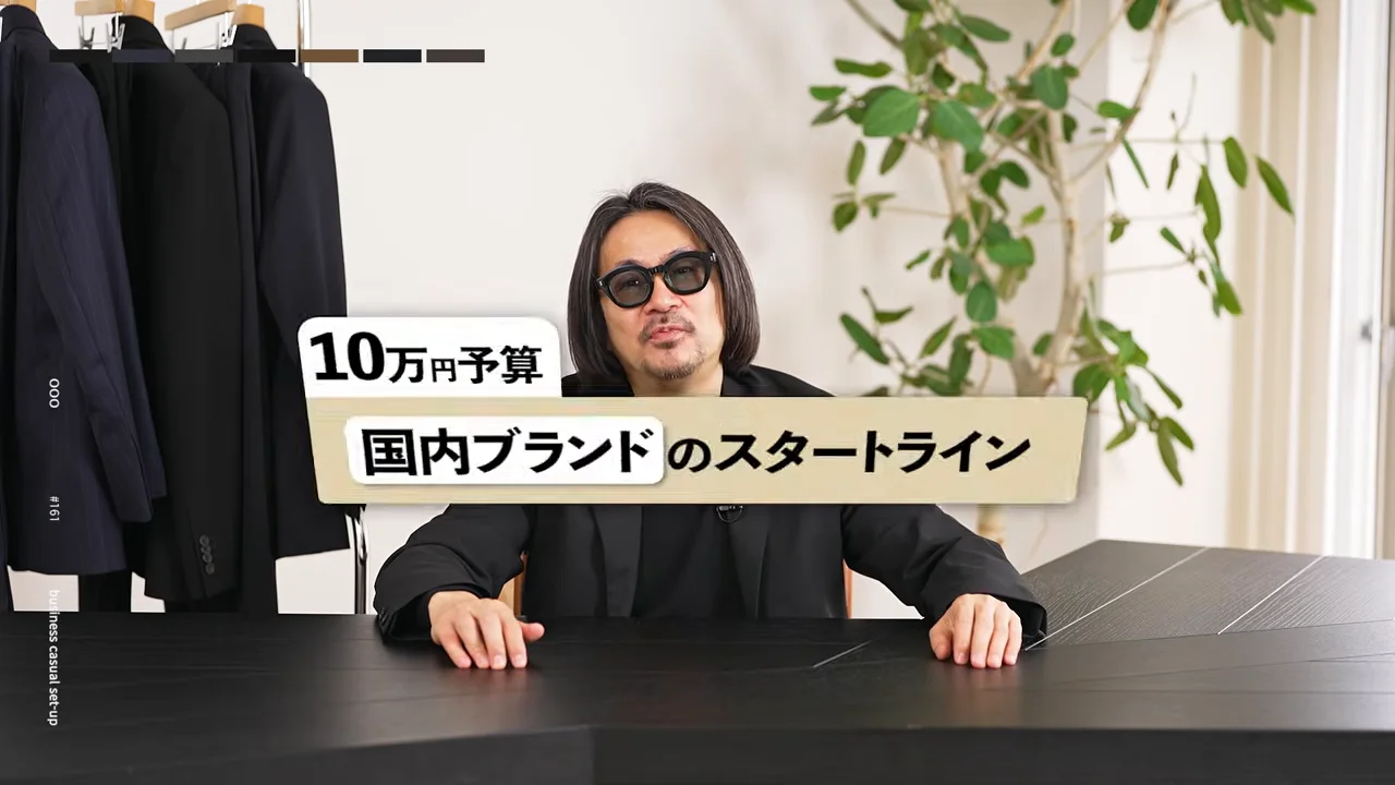 男性がテーブルに両手を広げて置き、正面を見据えています。