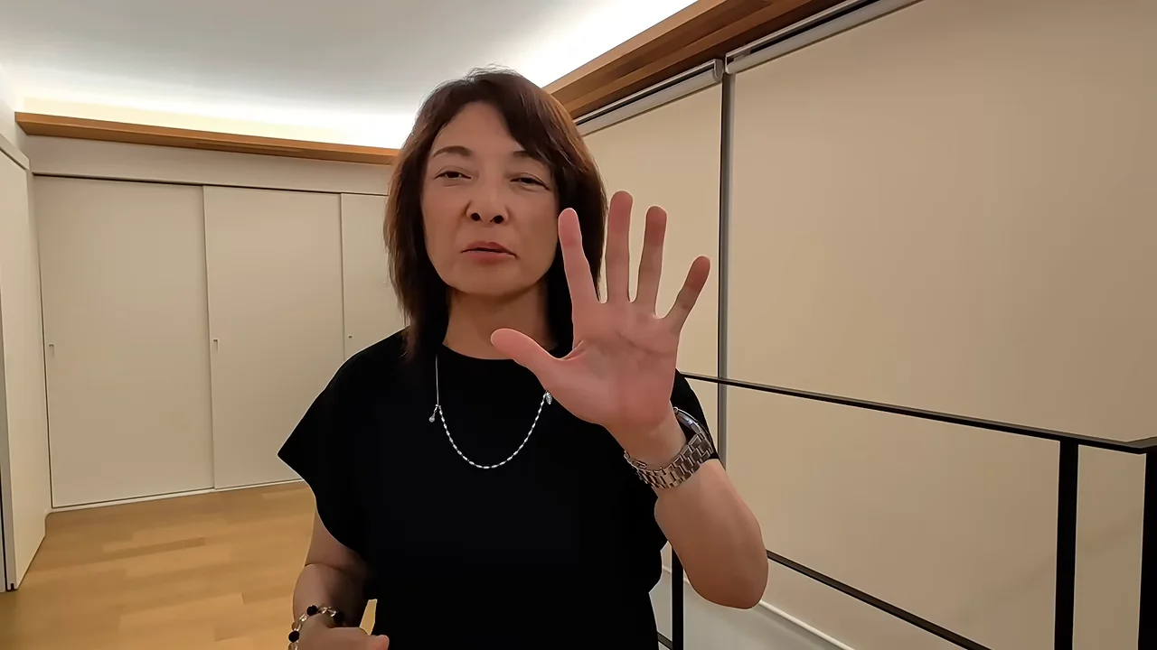 黒い服を着た女性がカメラに向かって手のひらを広げています。