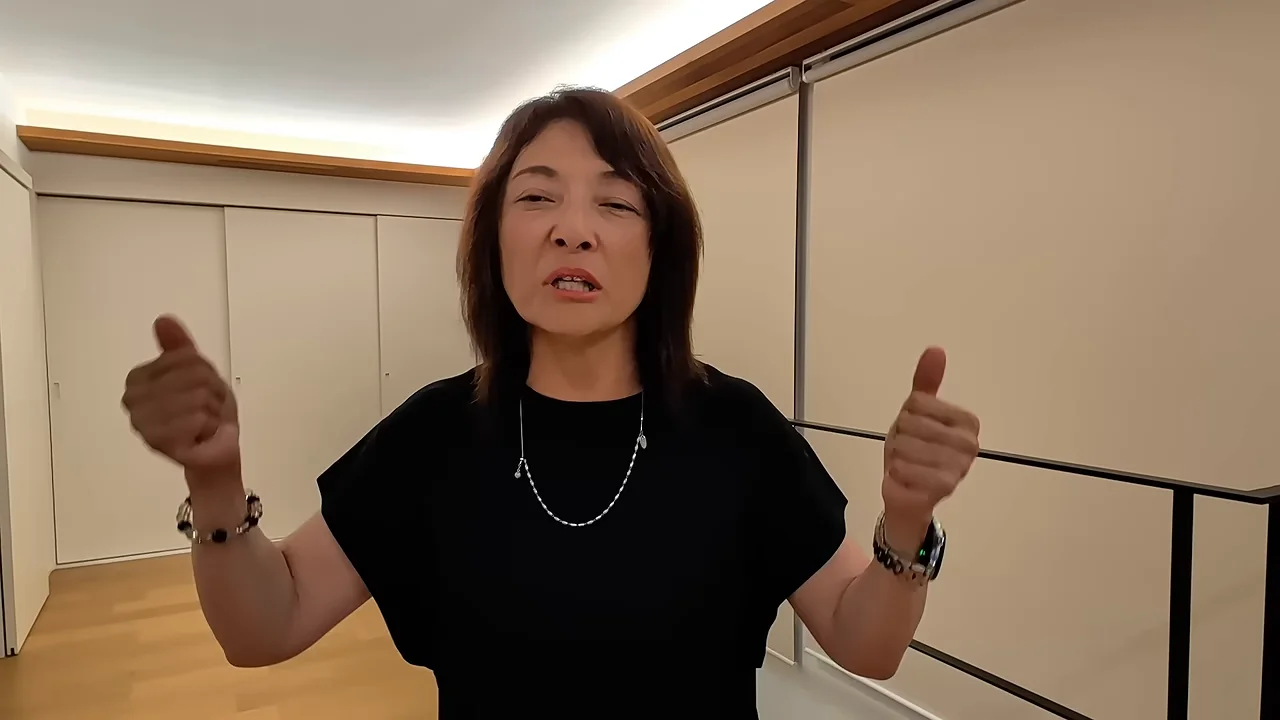 女性が両手の親指を立てるポーズをとって話しています。