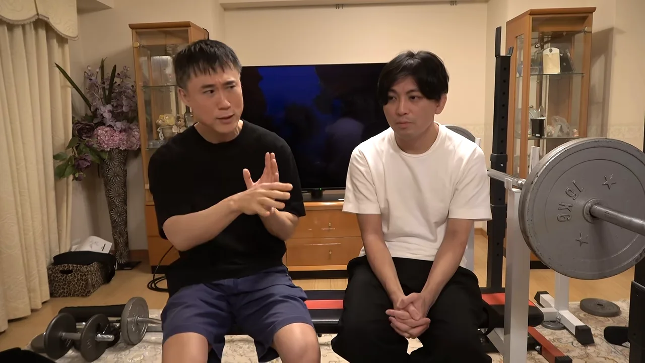 座って手振りで話している男性と、隣で聞いている男性の様子。
