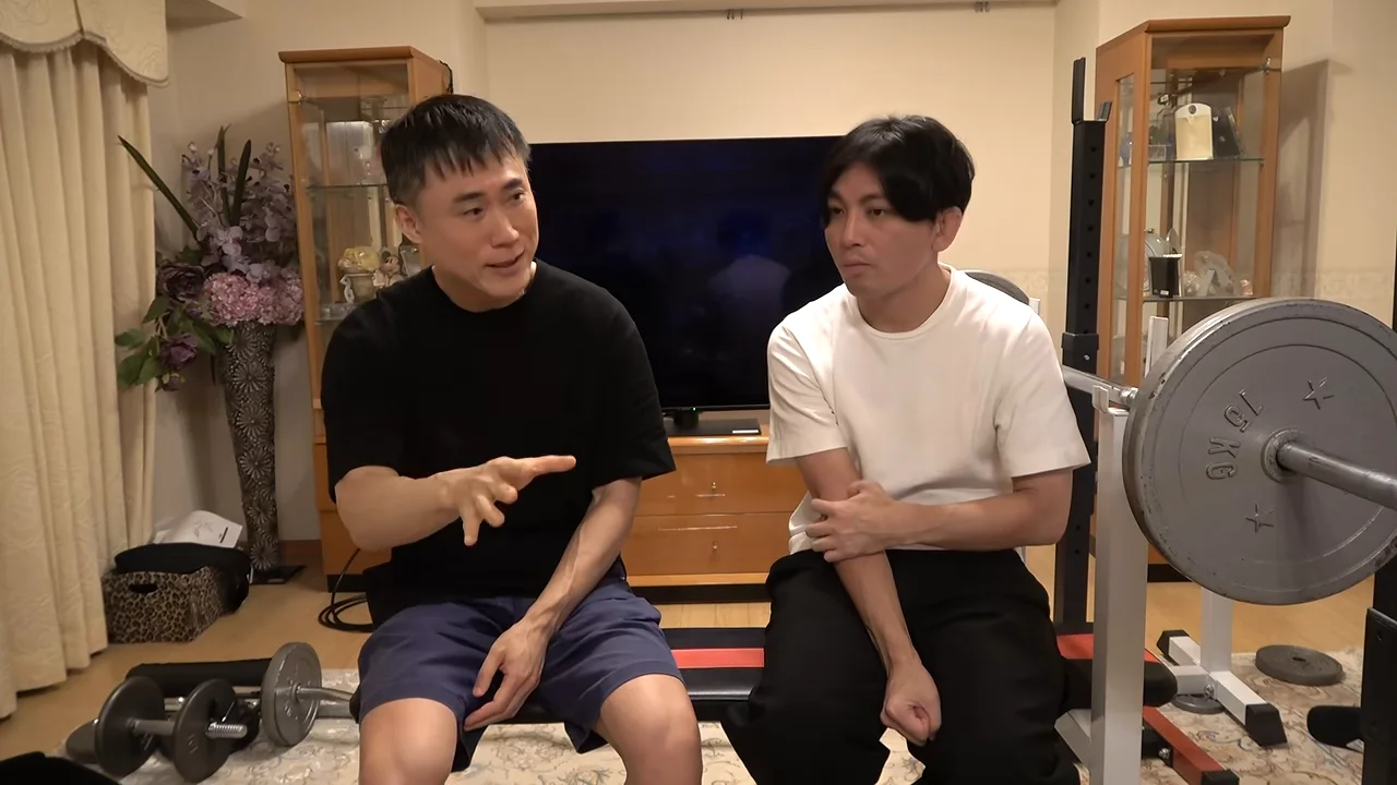 前方に手を向けながら話す男性と、腕に手を当てて聞いている男性の様子。