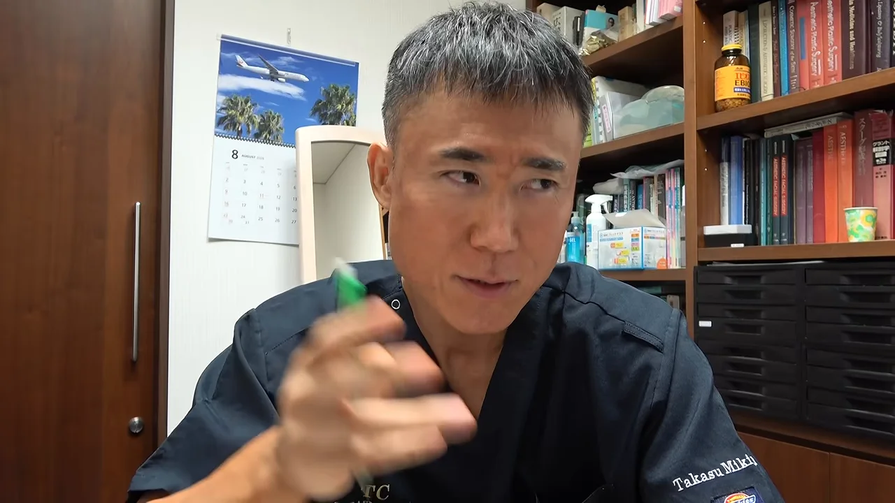緑色のペンを手にして身振り手振りを交えながら語る男性