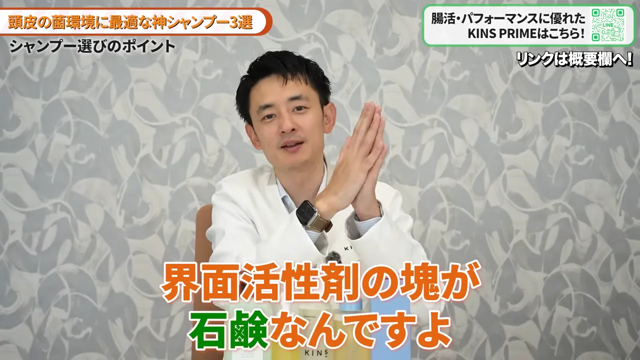 白衣を着た男性が胸の前で両手を合わせながら話している様子。