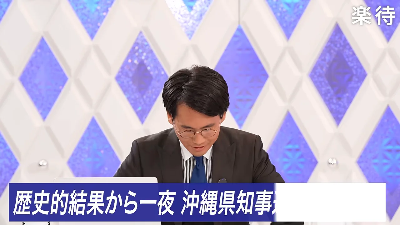 スタジオで手元に視線を落とすスーツ姿の男性が映し出されています。