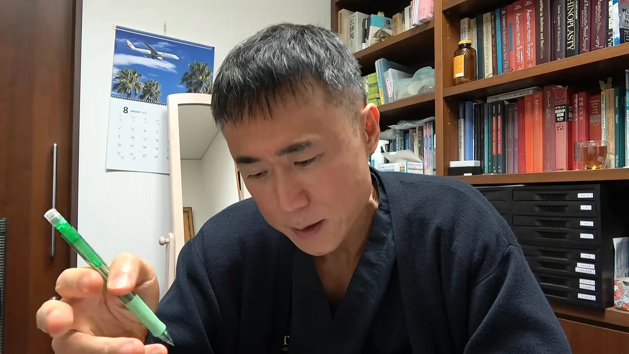 ペンを手にして下を向いて語る男性。