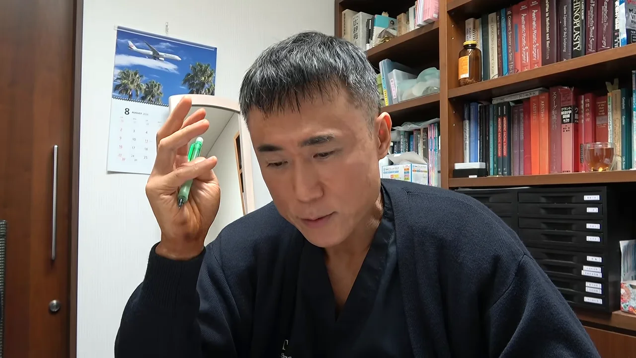 ペンを持った手を上に掲げて説明する男性。