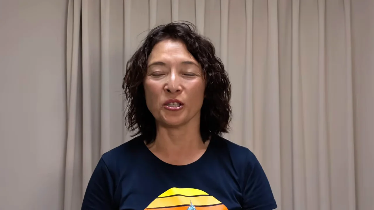 カーテンの前で女性が正面を向いて話している様子。