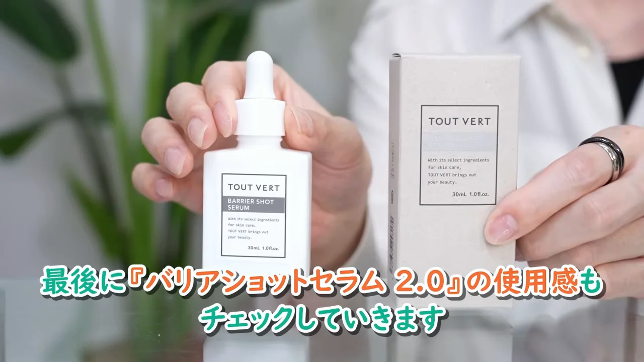 男性が「TOUT VERT BARRIER SHOT SERUM」のボトルと外箱を両手で持って見せている場面。