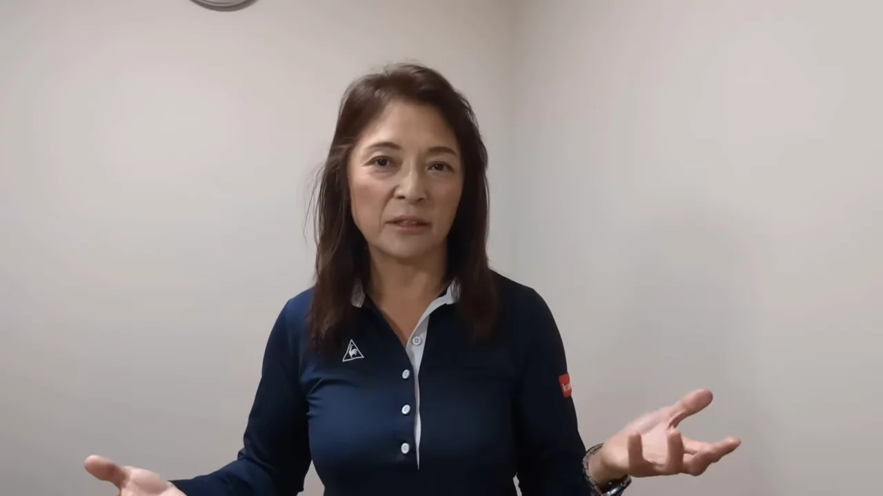 両手を広げてカメラに向かって話す女性の姿