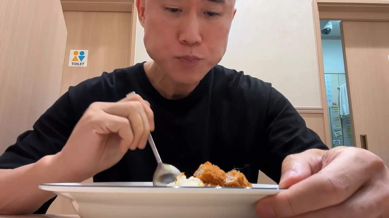 男性がスプーンで料理を食べながら味わっている様子。