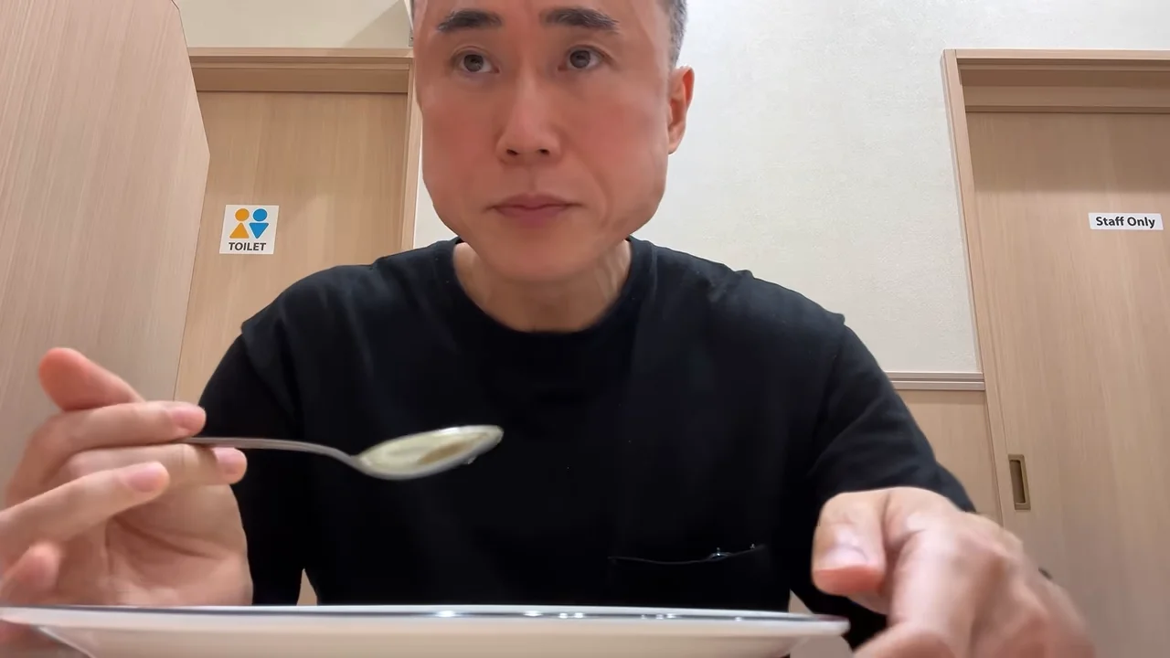 男性が食事を終えようとスプーンを口から離して前を見ている様子。