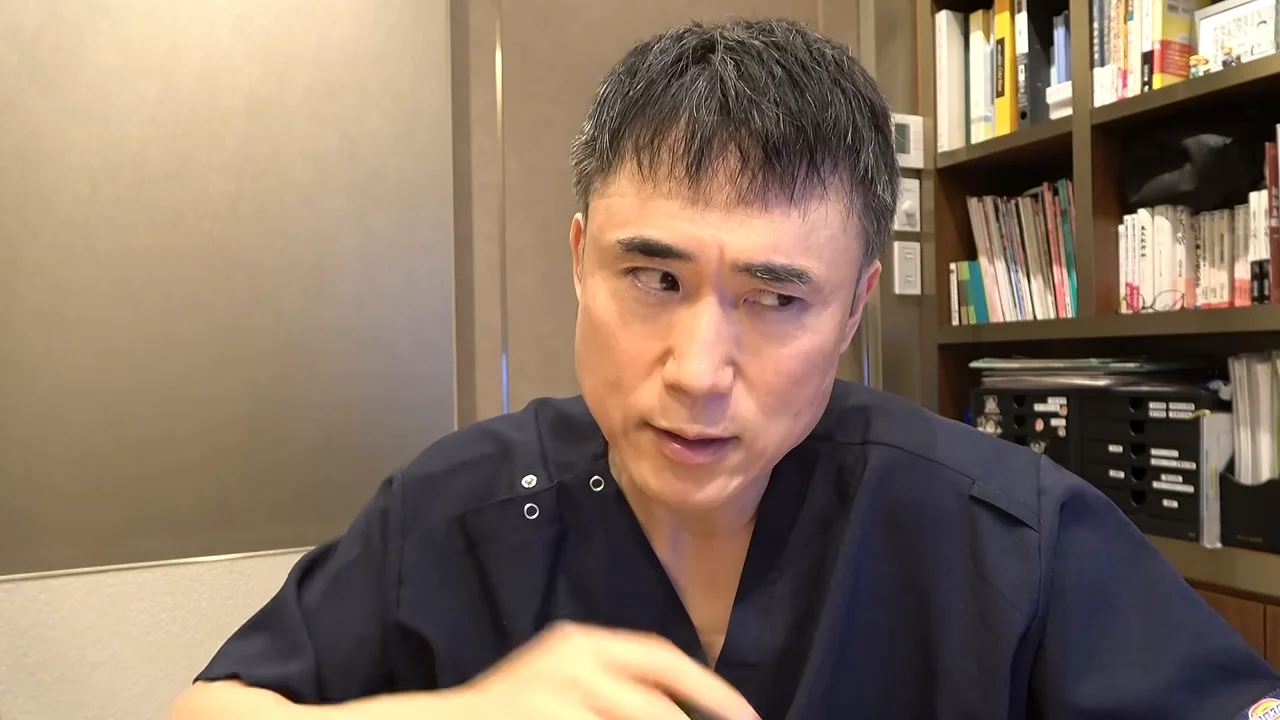 スクラブを着た男性が視線を斜め下に向けながら話している様子。