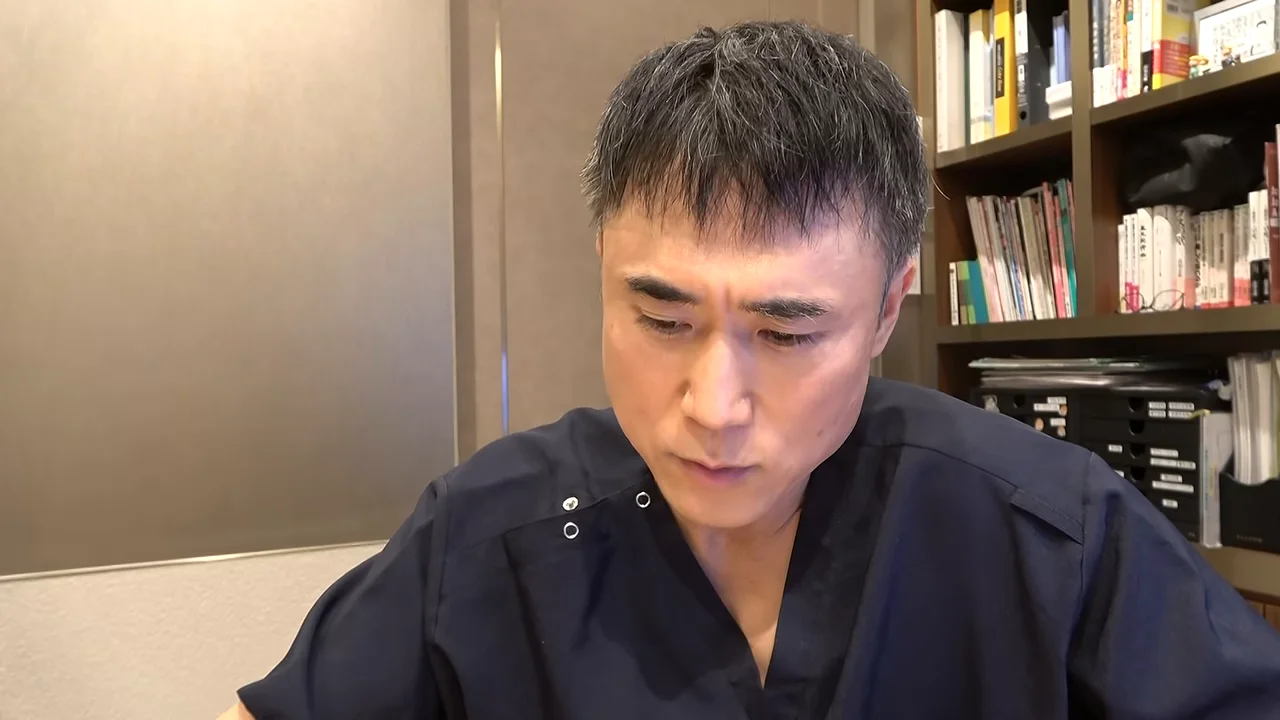 スクラブを着た男性がうつむき加減で真剣な表情を浮かべている様子。