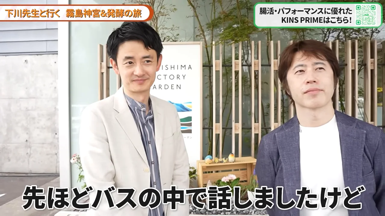 「KIRISHIMA FACTORY GARDEN」の看板の前に並んで立つ2人の男性の様子。