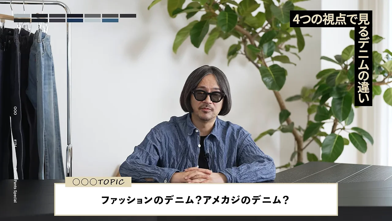 デニムが並ぶ部屋で男性がテーブルについて説明している様子