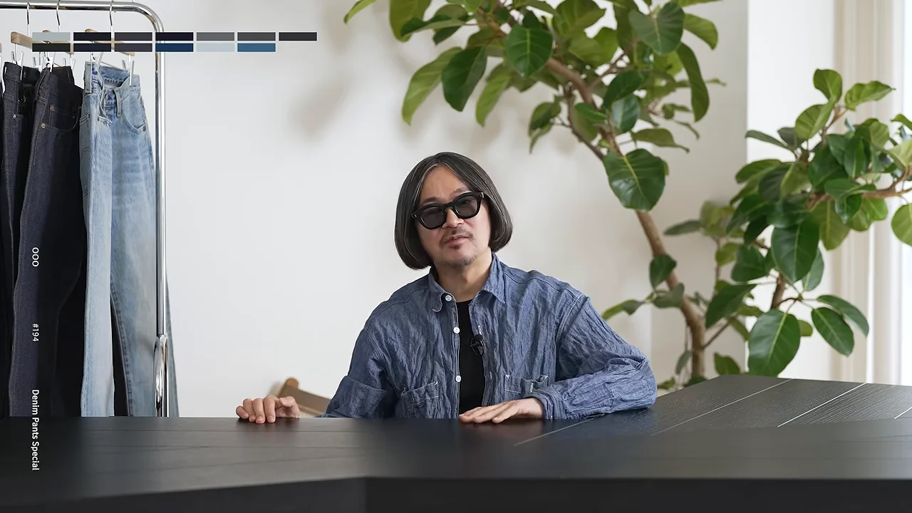 テーブルに手を置いて前を見つめながら話す男性の姿