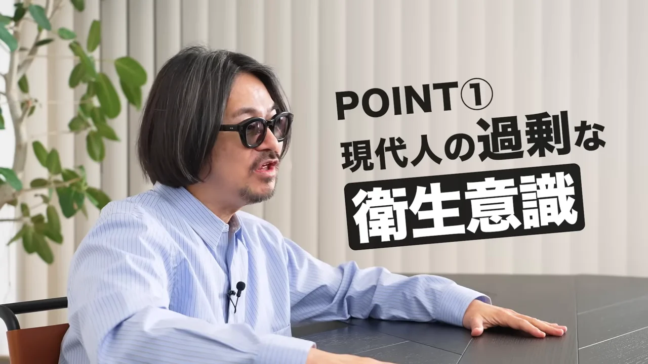 眼鏡をかけた男性が机の前に座り、文字テロップが表示されている様子。