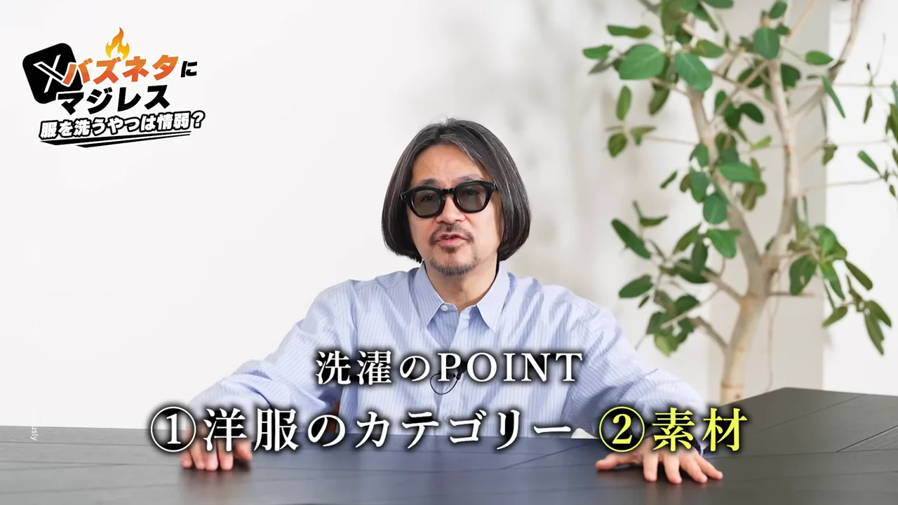 男性が机に両手を置き、洗濯のポイントに関するテロップが表示されている様子。