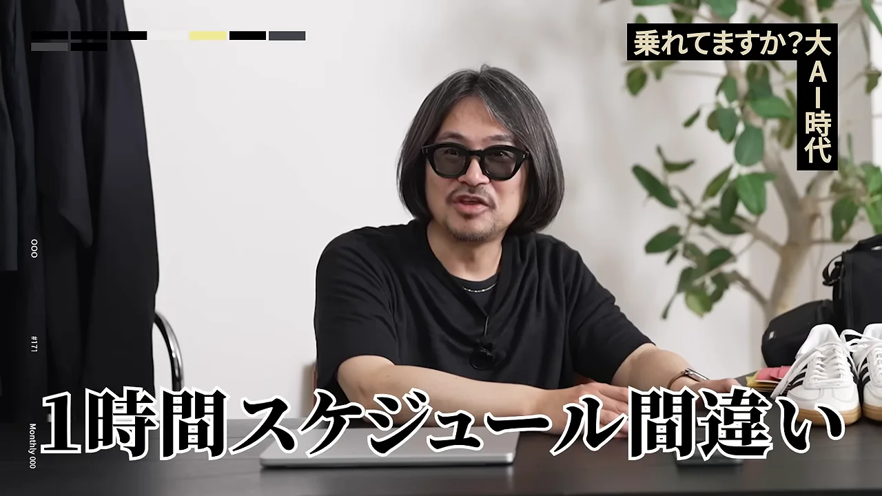 眼鏡をかけた男性がノートパソコンの置かれたテーブルの前に座り話している様子。