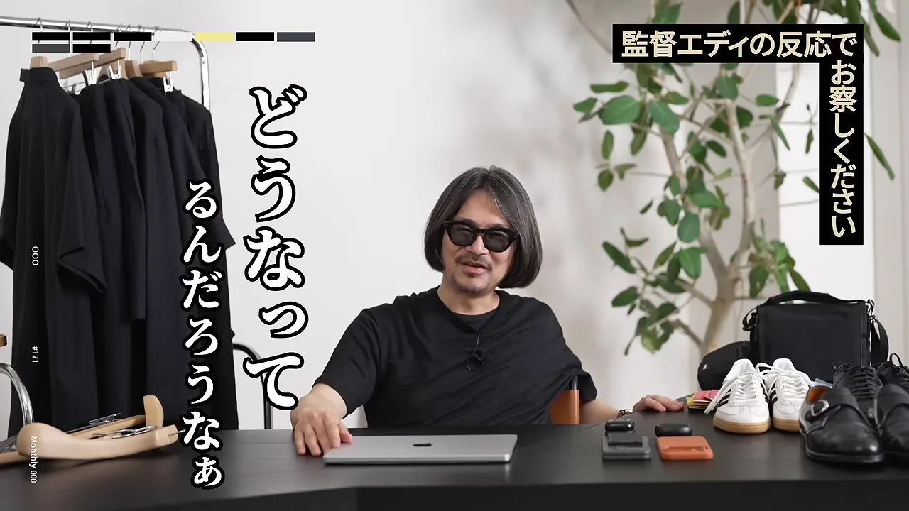 ノートパソコンが置かれたテーブルの前で、眼鏡をかけた男性が笑顔を浮かべている様子。