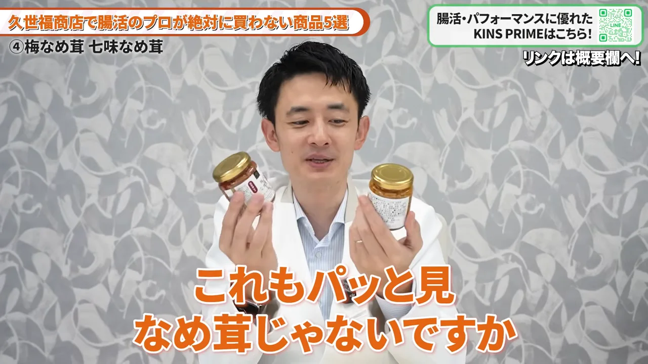 白衣を着た男性が両手に瓶詰めの食品を持ってカメラに向けている様子。